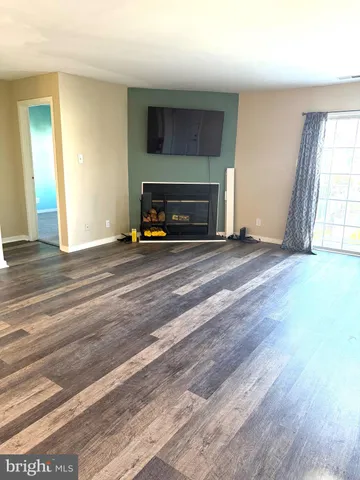 a view of empty room with wooden floor and fireplace