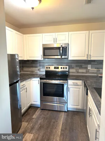 a kitchen with granite countertop a stove top oven microwave and refrigerator