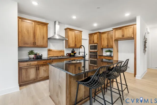 a kitchen with stainless steel appliances granite countertop a stove top oven a sink a refrigerator and white cabinets