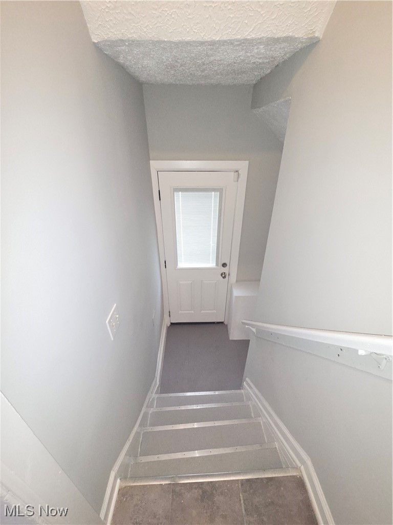 3797 Delmore Road Cleveland, OH 44121 - Photo 25 of 39 Staircase with tile patterned flooring and a textured ceiling