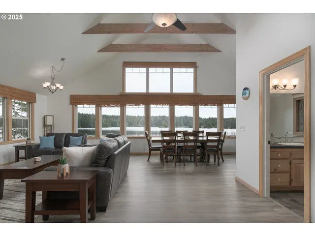 a living room with furniture a chandelier a large window and a flat screen tv