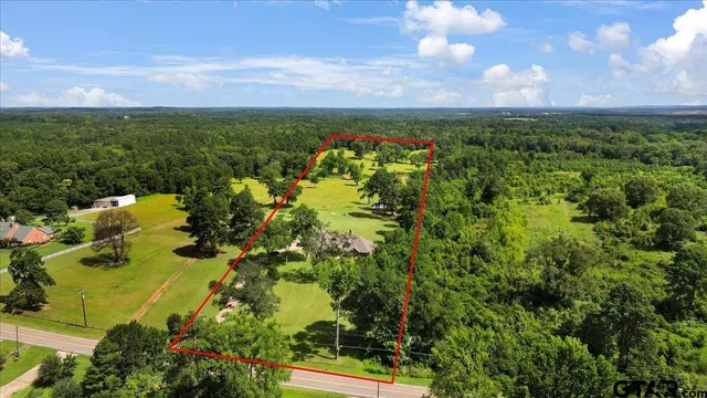 an aerial view of residential houses with outdoor space and trees all around