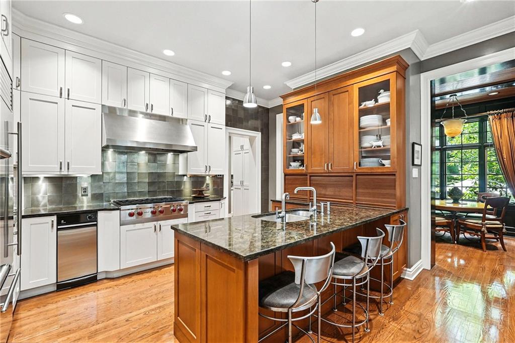 400 Devonshire Street Pittsburgh, PA 15213 - Photo 19 of 49 a kitchen with stainless steel appliances granite countertop a stove top oven a sink dishwasher a dining table and chairs with wooden floor