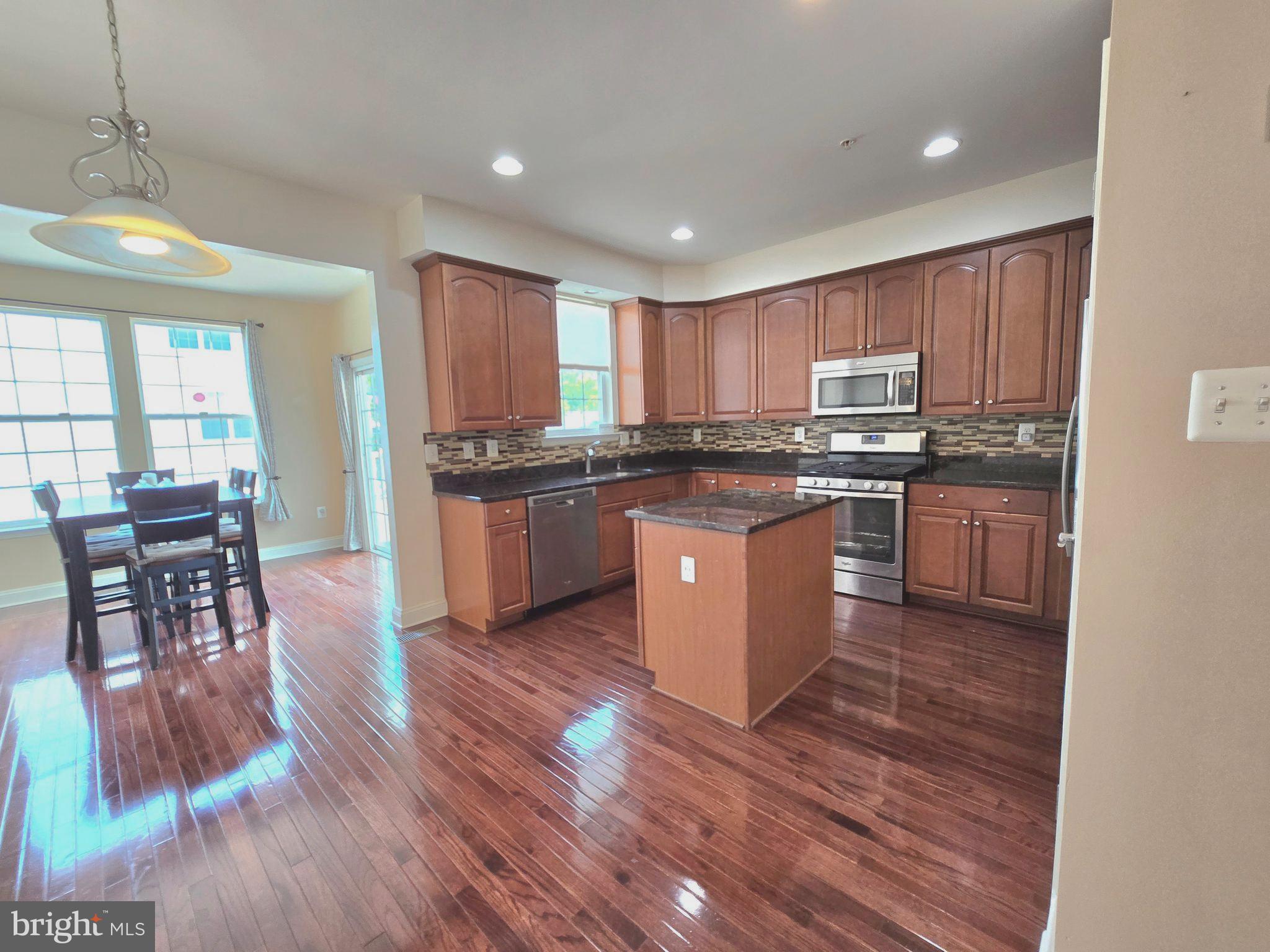 23012 Meadow Mist Road Clarksburg, MD 20871 - Photo 2 of 19 a kitchen with stainless steel appliances granite countertop wooden floors and wooden cabinets