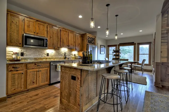 a kitchen with stainless steel appliances granite countertop a refrigerator a sink dishwasher a stove and white countertops with wooden floor