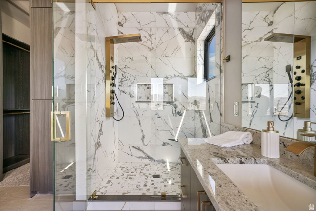 10646 North Reflection Ridge Hideout, UT 84036 - Photo 33 of 43 Glass-enclosed shower with gold-tone fixtures, full-height marble-patterned tile, and a mosaic tile floor