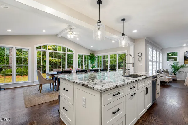 a kitchen with kitchen island granite countertop a sink a center island and stainless steel appliances