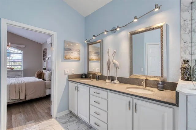 a large kitchen with stainless steel appliances granite countertop a refrigerator a stove top oven a sink dishwasher and white cabinets with wooden floor