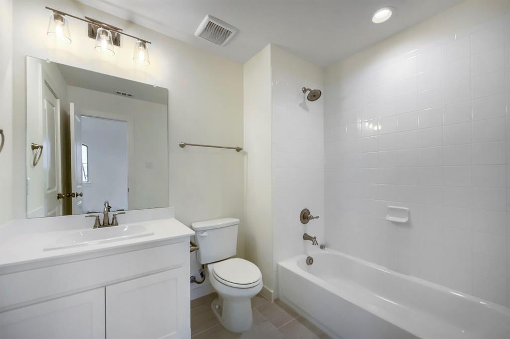 11548 Wulstone Road Haslet, TX 76052 - Photo 23 of 26 Bathroom featuring a white vanity with integrated sink, brushed nickel fixtures, a rectangular mirror, a toilet, and a bathtub with white subway tile surround