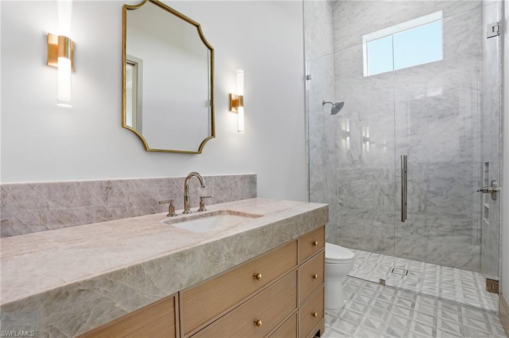 4851 Crayton Road Naples, FL 34103 - Photo 23 of 33 a bathroom with a granite countertop sink a mirror and shower