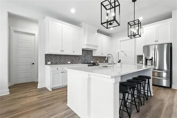 a kitchen with a refrigerator a sink and white cabinets
