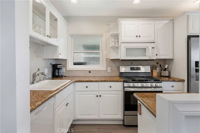 a kitchen with cabinets appliances a sink and a window