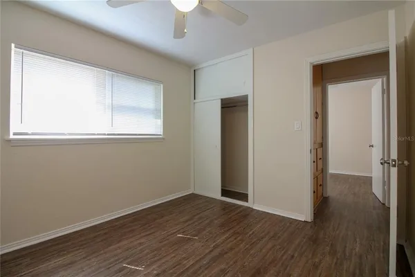 an empty room with wooden floor cabinet and windows
