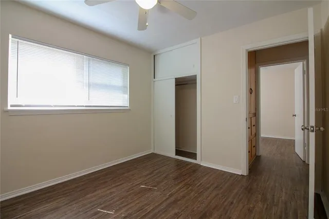 an empty room with wooden floor cabinet and windows