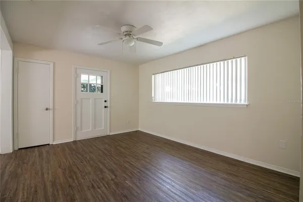 a view of an empty room with wooden floor and a window