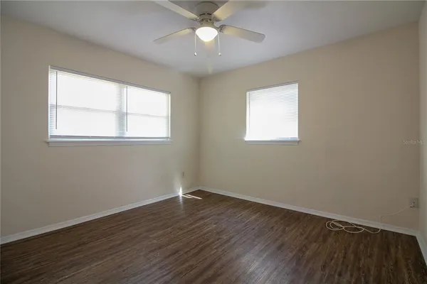 a view of an empty room with wooden floor and a window