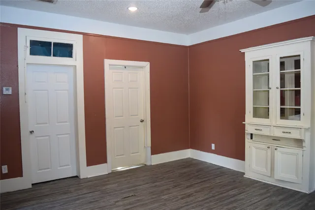 a view of an empty room with wooden floor and windows