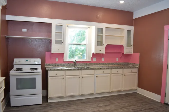 a kitchen with granite countertop a stove sink and cabinets