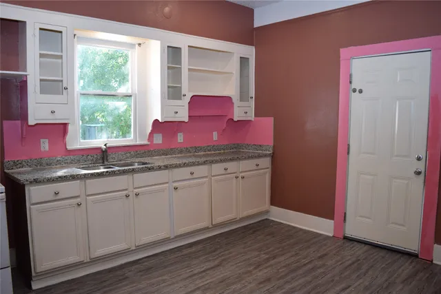 a kitchen with granite countertop kitchen island wooden floors and windows