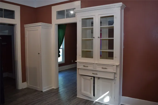a view of an empty room with wooden floor and a cabinet