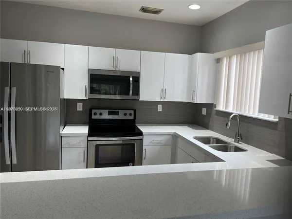 a kitchen with granite countertop a refrigerator and a sink