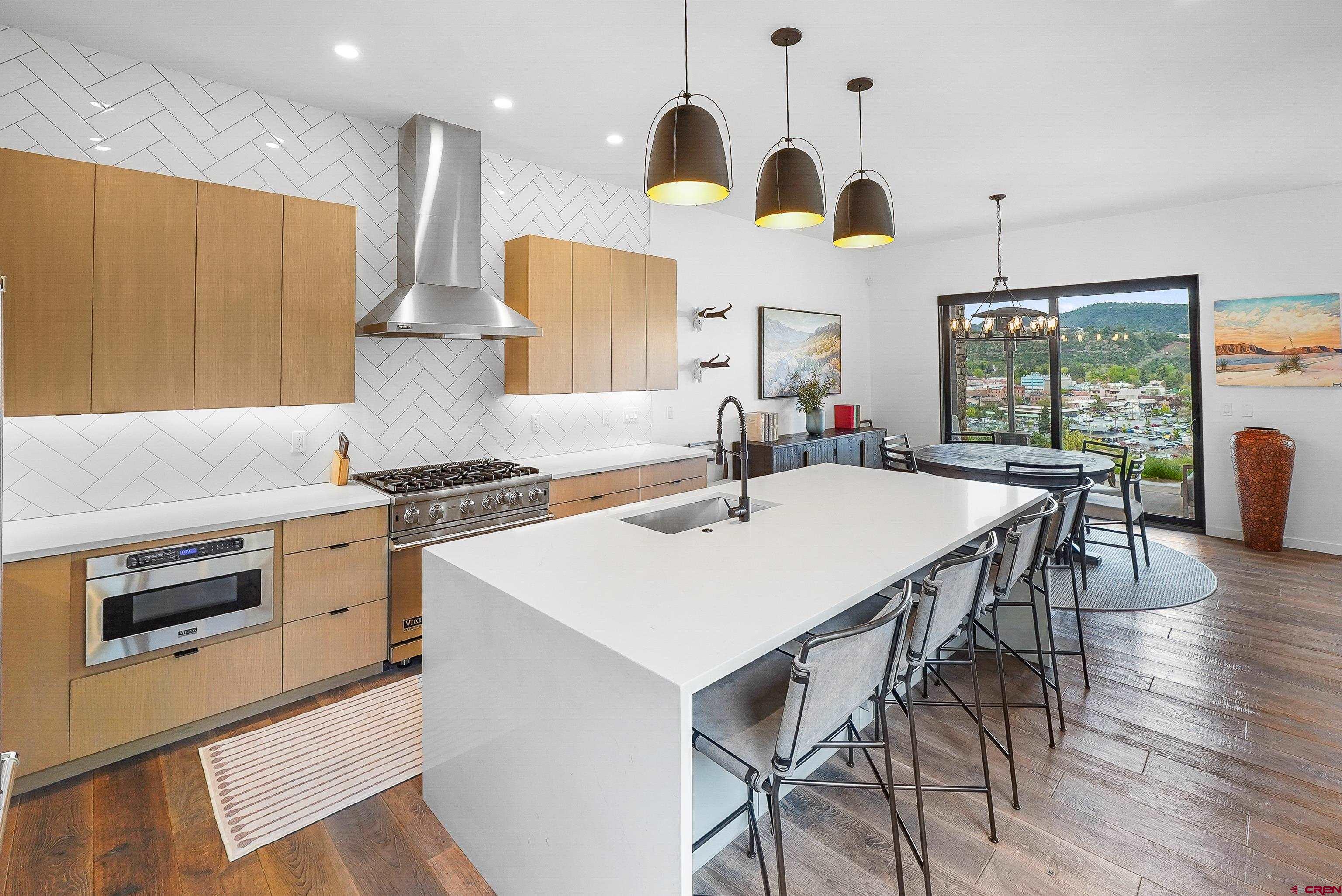239 Rock Point Drive, Unit B Durango, CO 81301 - Photo 15 of 45 a kitchen with stainless steel appliances kitchen island granite countertop a stove a sink a dining table and chairs with wooden floor