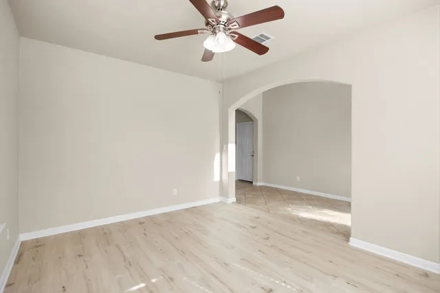 a view of an empty room with wooden floor and a window
