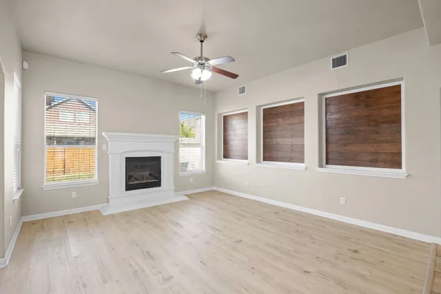 an empty room with windows and fireplace