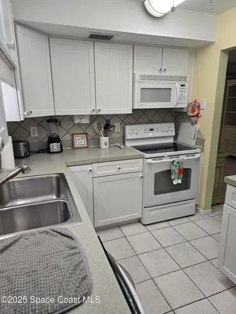 a kitchen with white cabinets a sink and white appliances