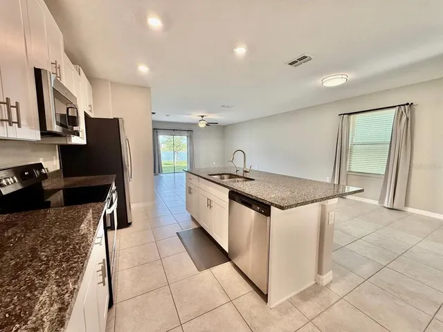 a kitchen with stainless steel appliances granite countertop a stove a sink and a refrigerator