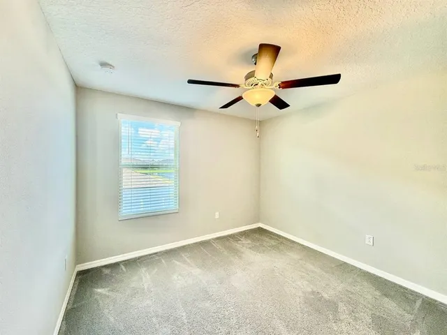 an empty room with a ceiling fan and a window