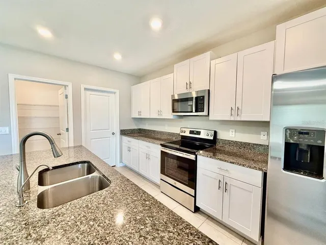 a kitchen with white cabinets a sink stove and microwave