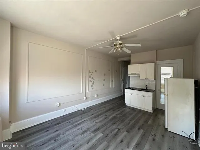 a large kitchen with a wooden floor and white cabinets