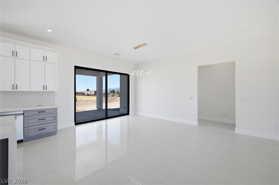 5910 East Kellogg Road Pahrump, NV 89061 - Photo 23 of 58 A spacious, open concept living area boasts sleek tile flooring and a view of the desert landscape.