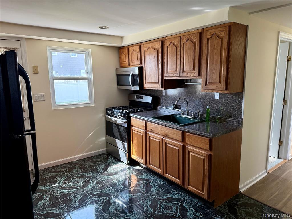 84 Surf Road Lindenhurst, NY 11757 - Photo 17 of 31 a kitchen with stainless steel appliances granite countertop a refrigerator stove and sink