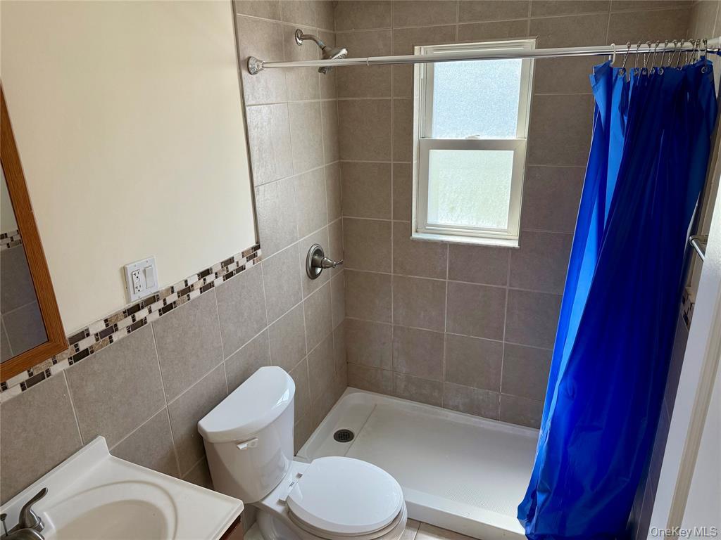 84 Surf Road Lindenhurst, NY 11757 - Photo 19 of 31 a white toilet sitting next to a bath tub and a shower