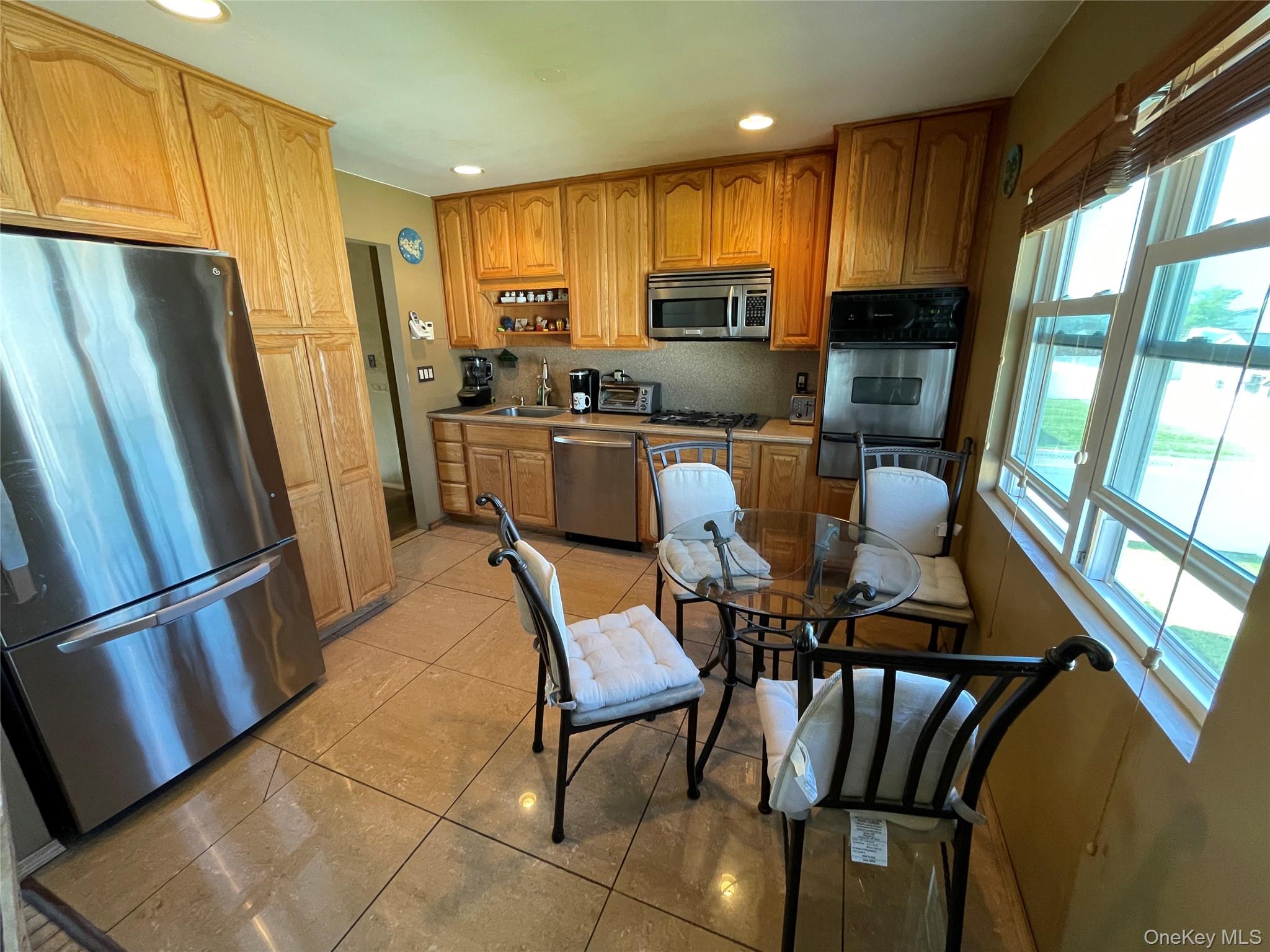 84 Surf Road Lindenhurst, NY 11757 - Photo 10 of 31 a kitchen with stainless steel appliances granite countertop a refrigerator a stove a microwave oven with a dining table and chairs
