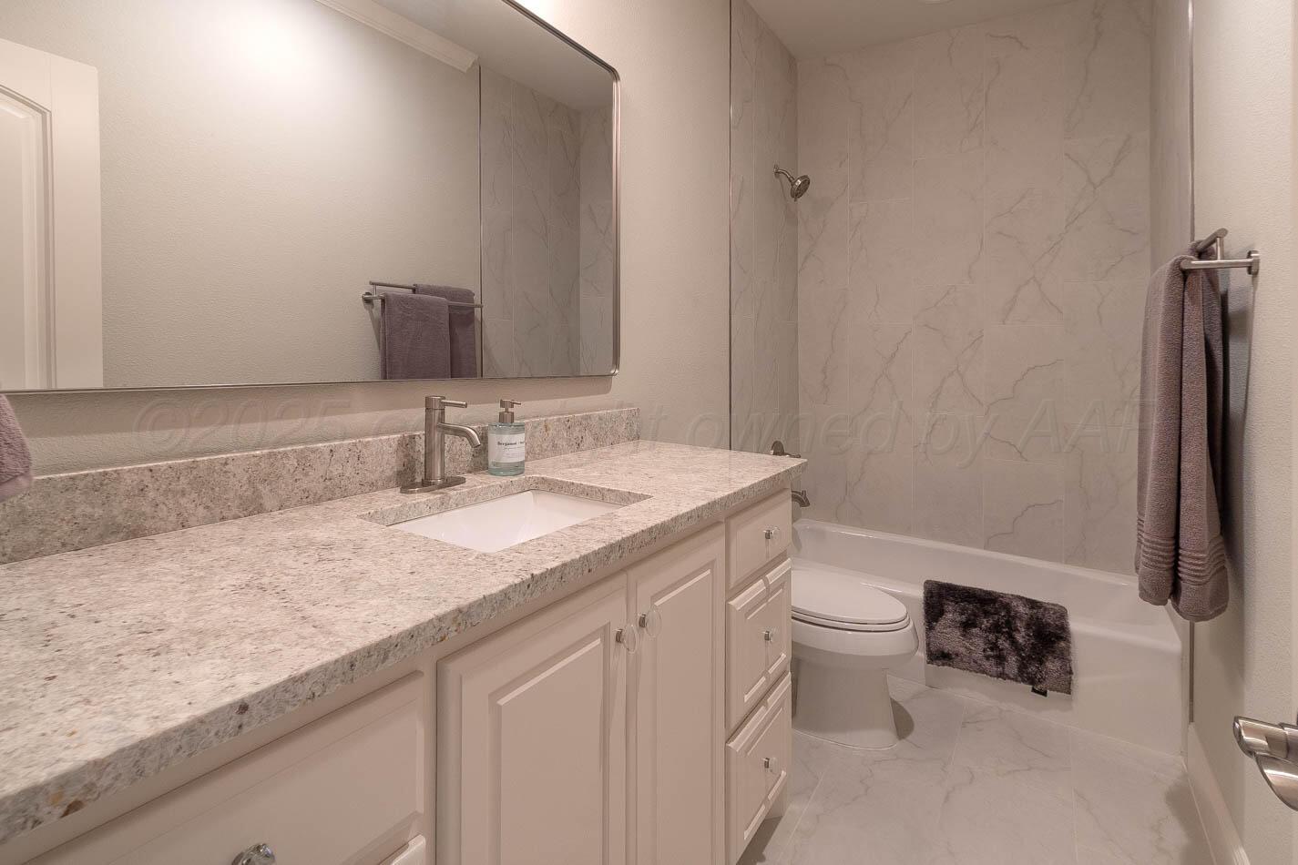 6809 Baccus Amarillo, TX 79124 - Photo 18 of 20 a bathroom with a granite countertop sink a toilet and a mirror
