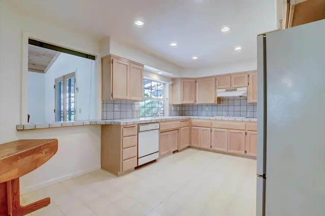 a kitchen with granite countertop white cabinets and white appliances