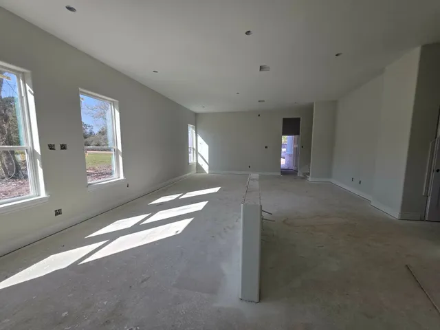 a view of an empty room with a window and a kitchen