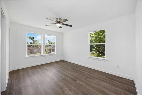a view of an empty room with wooden floor and a window