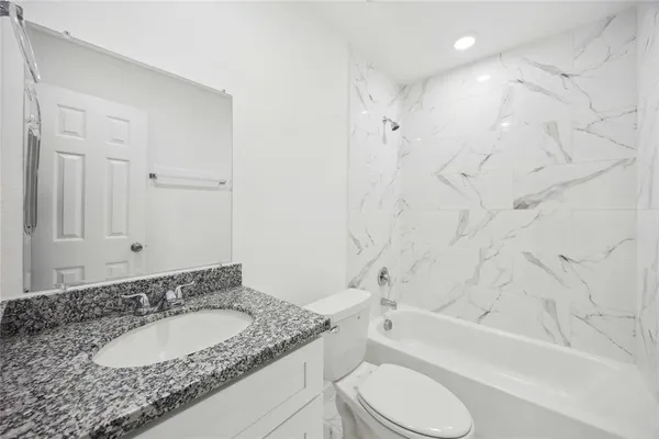 a bathroom with a granite countertop sink toilet bathtub and shower