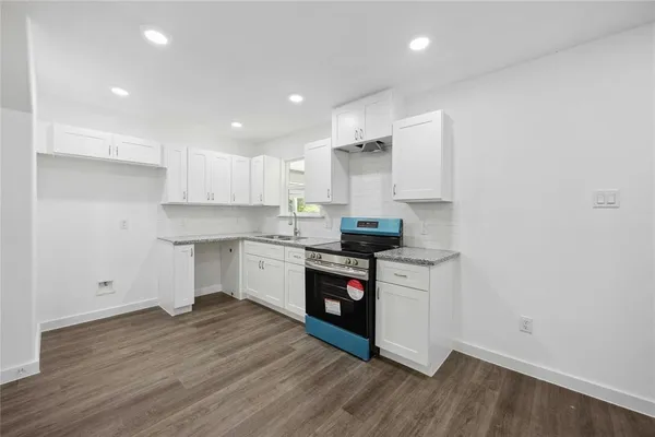 a kitchen with a white cabinets and wooden floor