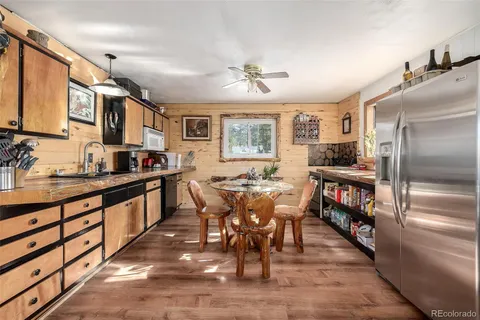 a kitchen with stainless steel appliances kitchen island granite countertop a table chairs and a refrigerator