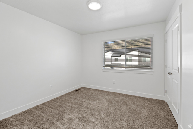 1271 West 500 South Logan, UT 84321 - Photo 24 of 26 Carpeted room with a window featuring blinds, a flush mount ceiling light, and a white paneled door with a silver handle