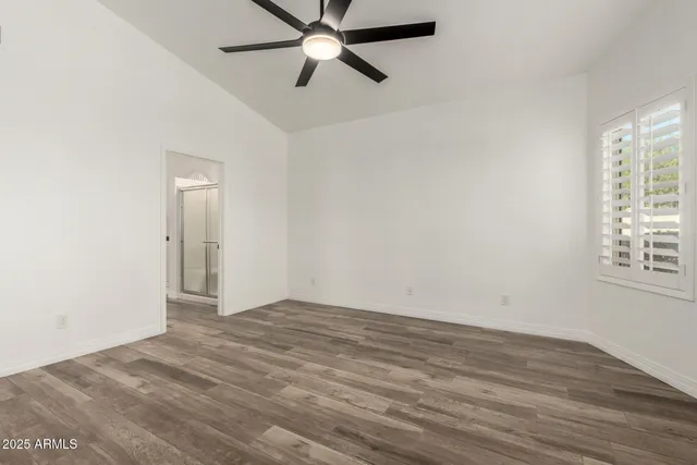 an empty room with wooden floor fan and windows
