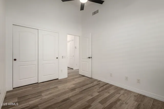 a view of an empty room with window and chandelier fan