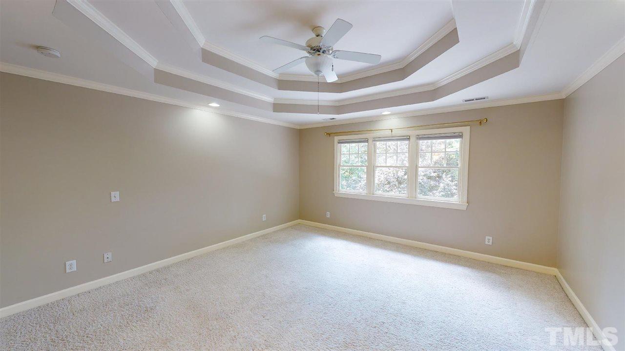 8212 Gaspari Court Raleigh, NC 27615 - Photo 12 of 18 an empty room with a chandelier fan and windows