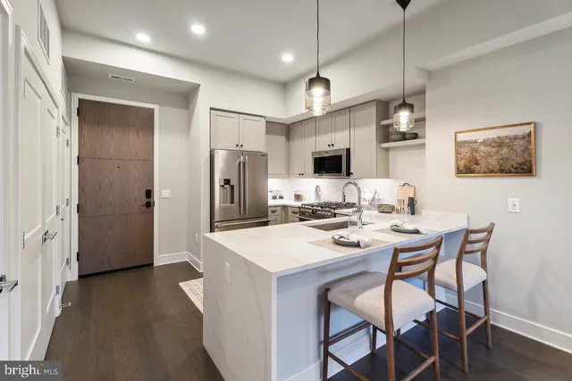 a kitchen with stainless steel appliances kitchen island a table chairs and wooden floor
