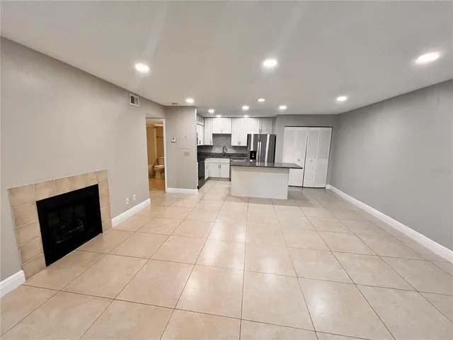 a open kitchen with kitchen island granite countertop a rug and a view of living room
